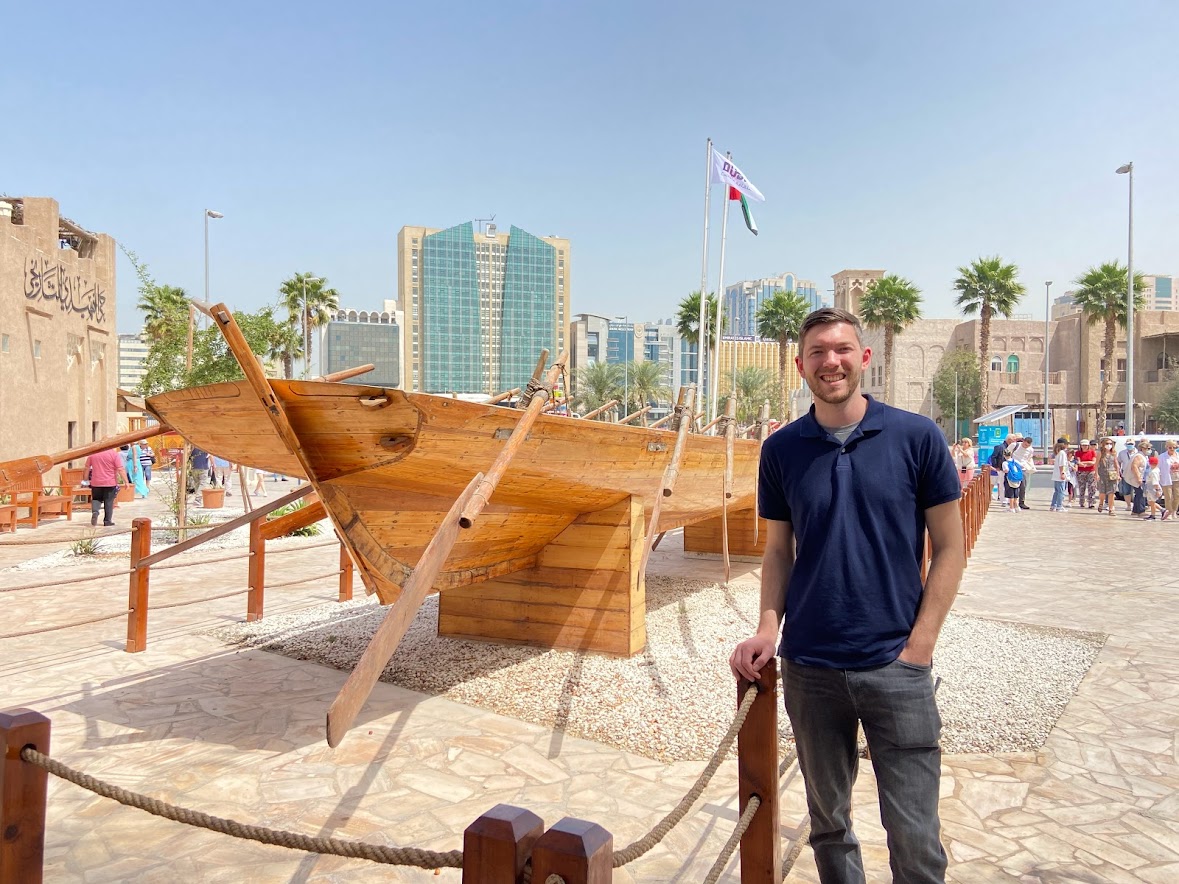 A man standing infront of a traditional style boat